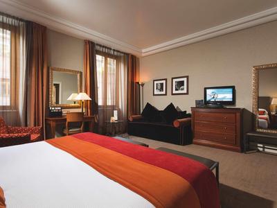 Chambre d'hôtel confortable avec lit double, coin salon et télévision aux tons chauds.