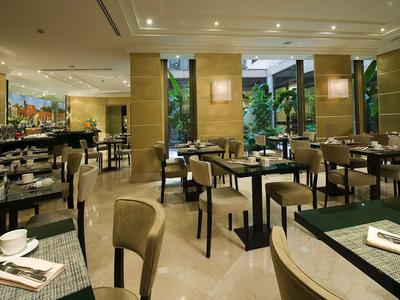 Restaurant d'hôtel moderne avec tables dressées et vue sur une terrasse verte.