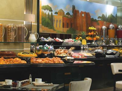 Buffet d'hôtel avec diverses nourritures, céréales, jus et une peinture murale décorative.