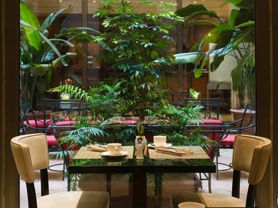 Une table dressée pour deux avec vue sur une cour intérieure verdoyante de l'hôtel.