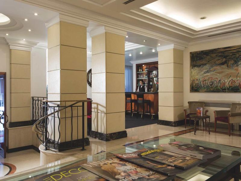 Hall d'hôtel lumineux avec réception et espace de sièges, éclairage moderne et art mural décoratif.