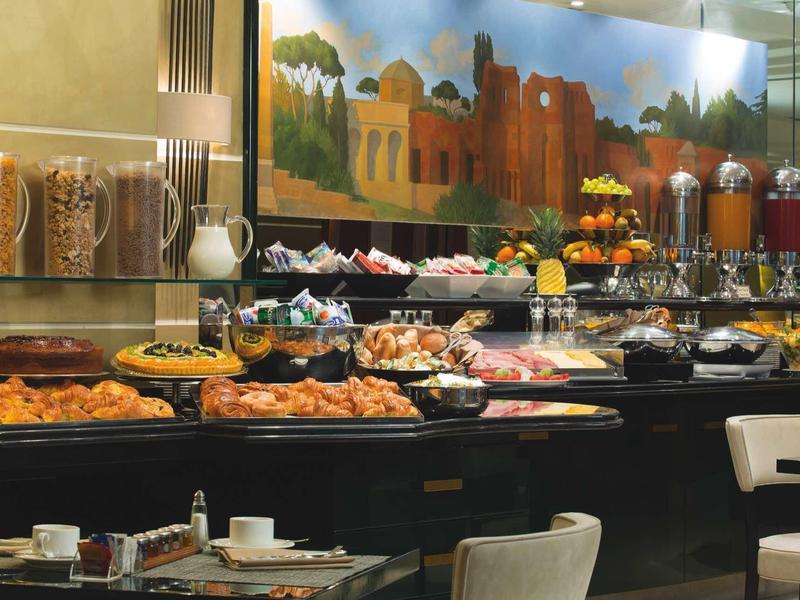 Buffet d'hôtel avec diverses nourritures, céréales, jus et une peinture murale décorative.