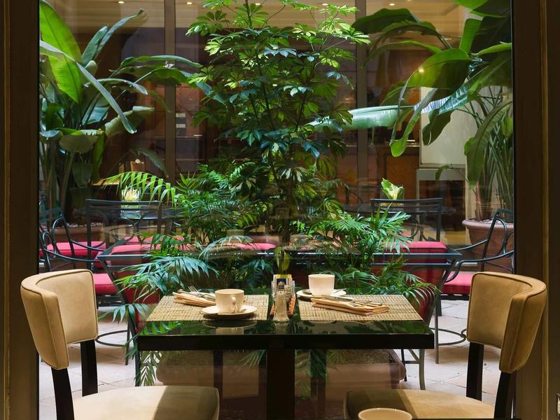 Une table dressée pour deux avec vue sur une cour intérieure verdoyante de l'hôtel.