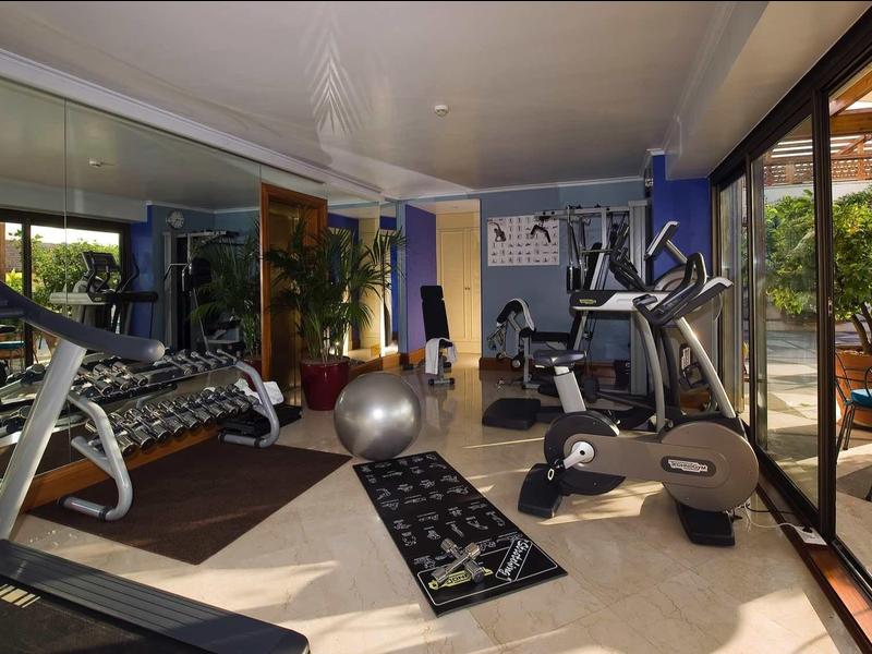 Salle de sport moderne avec équipements et vue sur une terrasse d'hôtel.