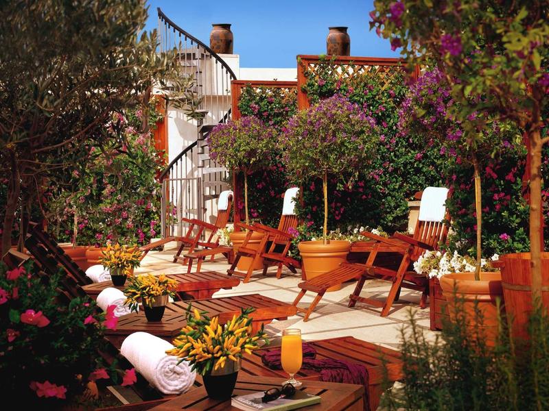 Terrasse ensoleillée avec chaises longues en bois, serviettes et plantes dans un lieu de vacances.