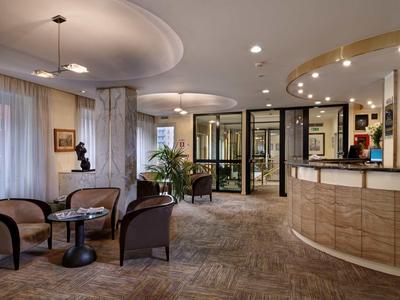 Elegancka lobby hotelowa z miejscem do siedzenia, recepcją i nowoczesnym oświetleniem.