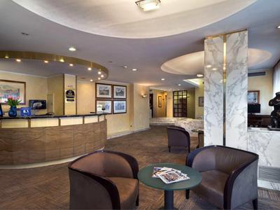 Elegancka lobby hotelowa z recepcją, miejscem do siedzenia i nowoczesnym oświetleniem.