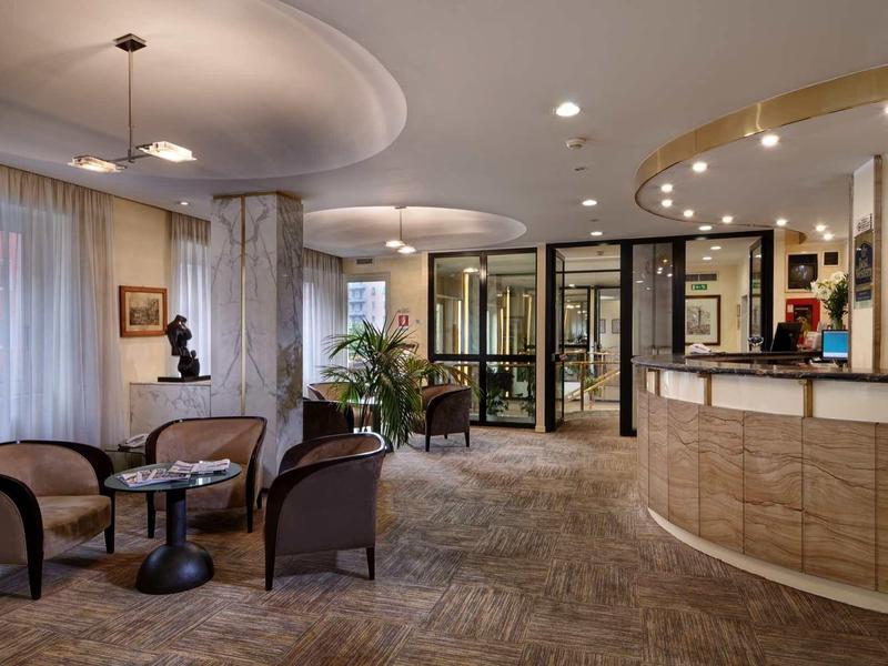 Elegancka lobby hotelowa z miejscem do siedzenia, recepcją i nowoczesnym oświetleniem.