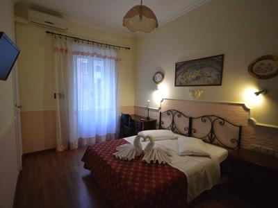 Habitación de hotel acogedora con cama doble, lámparas de pared y TV en la pared