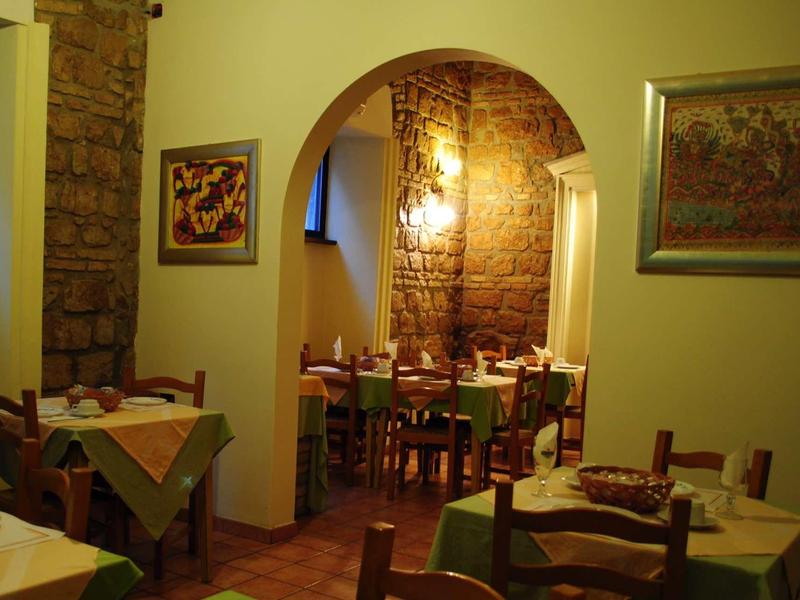 Gemütliches Restaurant mit Holztischen, grünen Tischdecken und rustikalen Wandlampen.