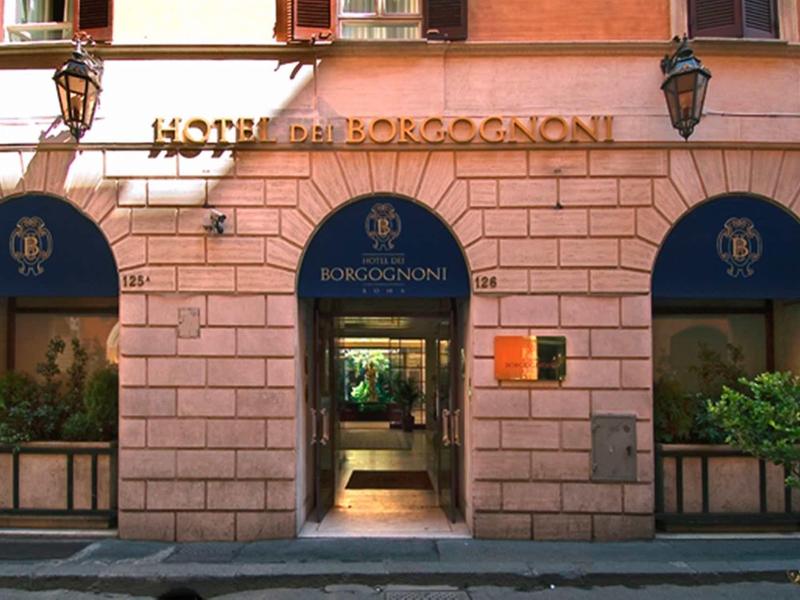 Fasáda hotelu Borgognoni s třemi modrými markýzami a centrálním vchodem.