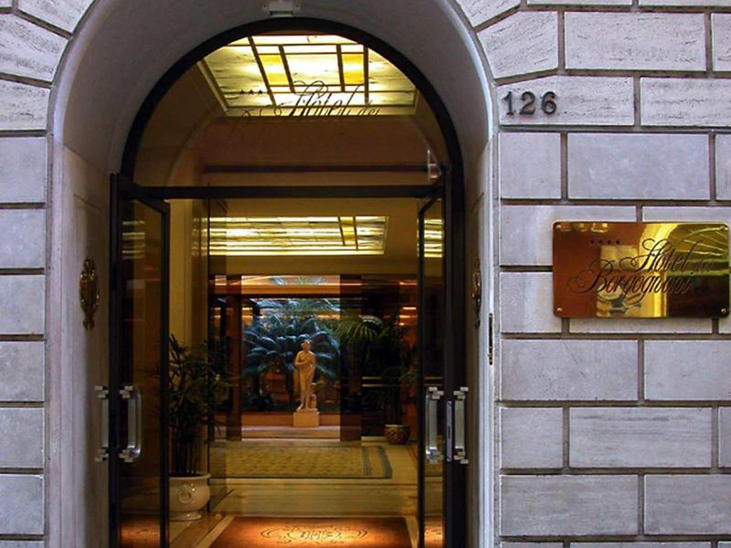 Otevřené dveře hotelu v elegantním kamenném oblouku s viditelnou recepcí uvnitř