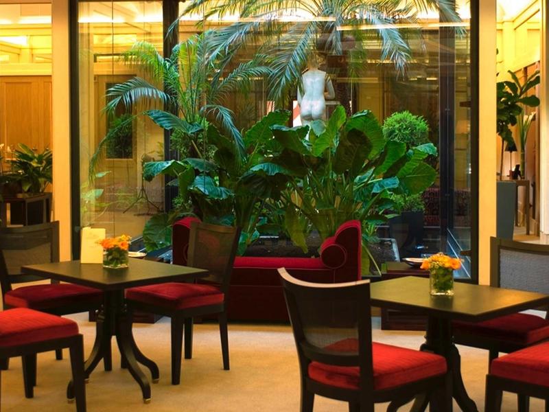Pohodlná sezení s červenými židlemi a zelenými rostlinami ve vnitřním atriu.