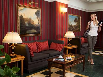 Wohnzimmer mit dunklem Sofa, roten Kissen, Tischlampen und einem Gemälde vor rot gestreifter Wand