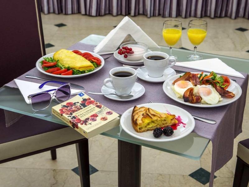 Varied breakfast with eggs, pastries, berries, coffee, and orange juice on a set hotel table.