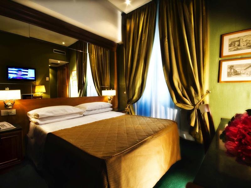 Cozy hotel room with double bed, green walls, and heavy curtains.