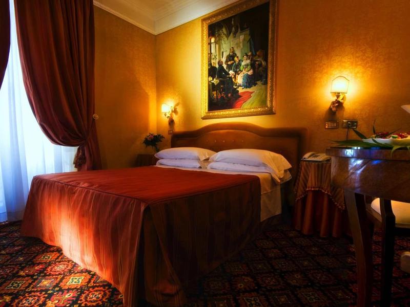 Cozy hotel room with double bed, warm lighting, and elegant decor.