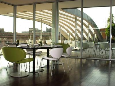 Modernes Restaurant mit großen Glasfenstern und bunten Stühlen in einem Hotel.
