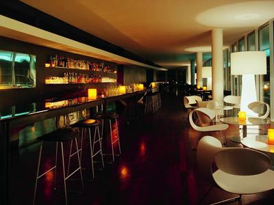Moderne Bar mit hohen Hockern und elegantem Sitzbereich, warm beleuchtet und stilvoll eingerichtet.
