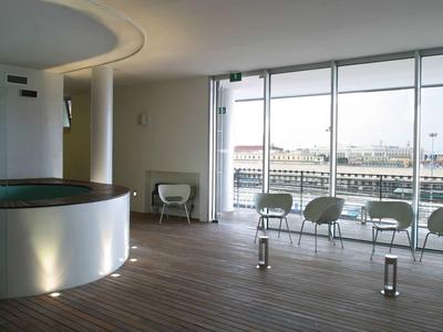 Moderner Raum mit hellen Wänden, großem Fenster, Holzboden und transparentem runden Tresen.