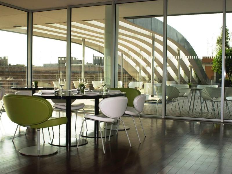 Moderne Café-Innenansicht mit grünen und weißen Stühlen, Glastischen und großem Fenster.