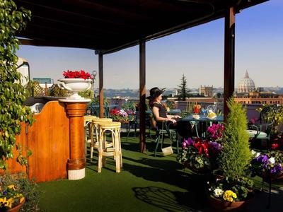 Terrasse couverte avec coin salon et vue sur la ville par temps ensoleillé.