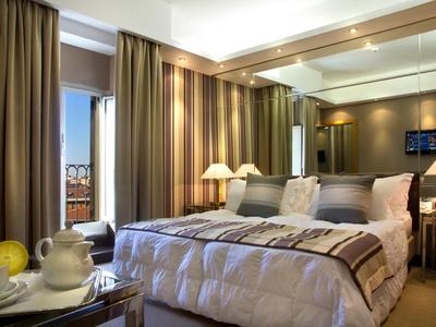 Chambre d'hôtel confortable avec grand lit, fenêtre avec rideaux et éclairage d'ambiance.