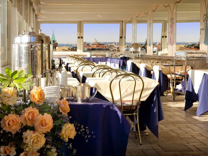 Salle de restaurant lumineuse avec nappes bleues et vue sur la ville et l'eau.