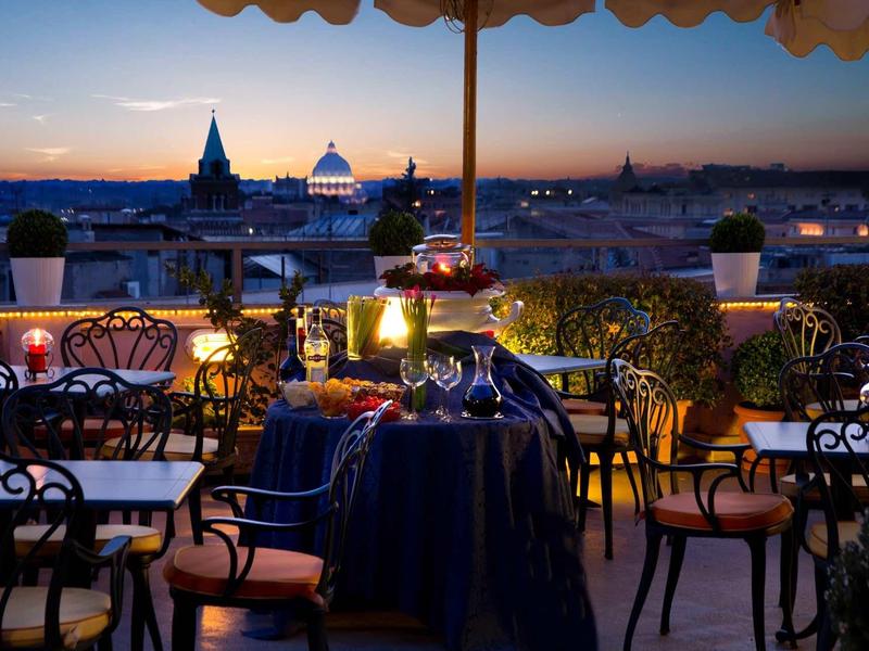 Dîner romantique sur une terrasse sur le toit avec vue sur une ville au coucher du soleil.