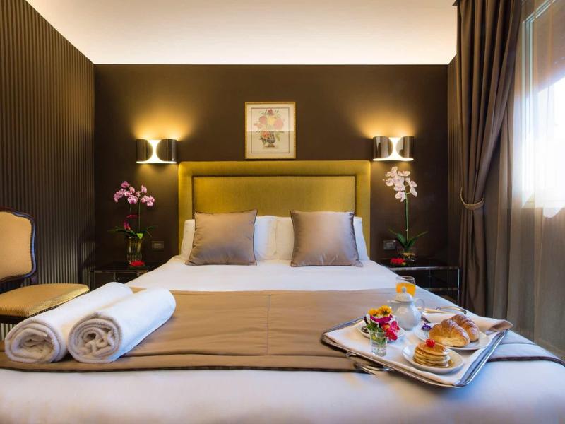 Chambre d'hôtel confortable avec lit double, éclairage chaleureux et plateau de petit-déjeuner.