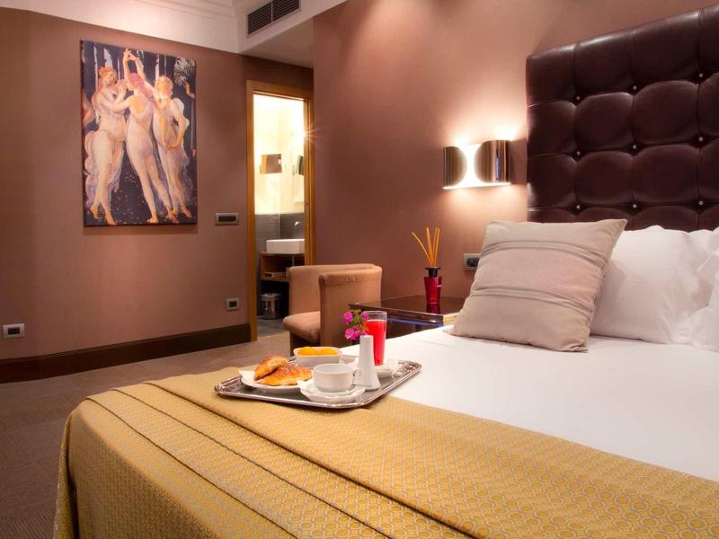 Chambre d'hôtel confortable avec lit douillet, œuvre murale et plateau de petit-déjeuner.