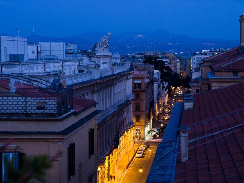 Vue sur une rue de la vieille ville illuminée au crépuscule avec des montagnes en arrière-plan.