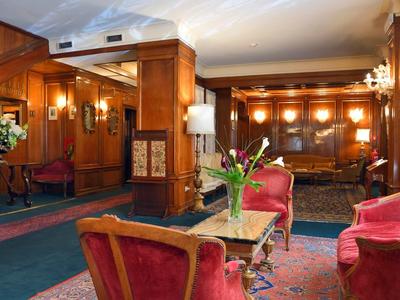 Elegante Hotellobby mit roten Samtsofas, Holzwänden und warmem Licht.