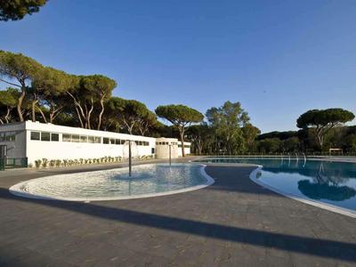 Piscine vide avec bâtiment moderne et pins sous un ciel clair