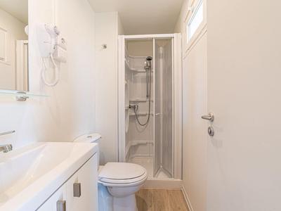 Kleine moderne badkamer met douche, toilet en wastafel in neutrale tinten.