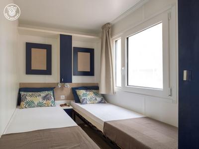 Kleine hotelkamer met twee eenpersoonsbedden, donkere hoofdeinden en groot raam