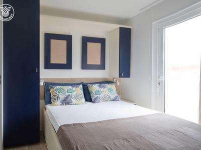 Gezellige slaapkamer met tweepersoonsbed, blauwe kasten en grote glazen deur