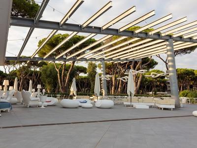 Espace extérieur moderne avec mobilier lounge blanc et auvent sous les arbres.