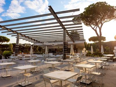 Leeg buitenterras van een hotel met tafels, stoelen en moderne pergola bij zonsondergang.