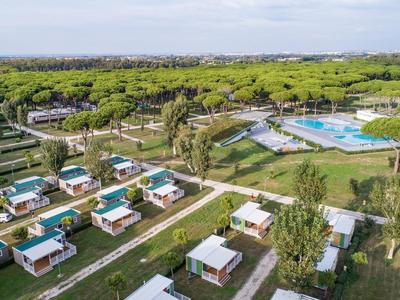 Luchtfoto van een resort met kleine moderne bungalows, zwembad en veel groen.