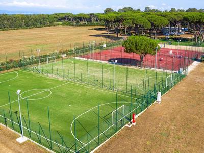 Installation sportive extérieure avec terrains de football et de tennis à côté des champs et des arbres.