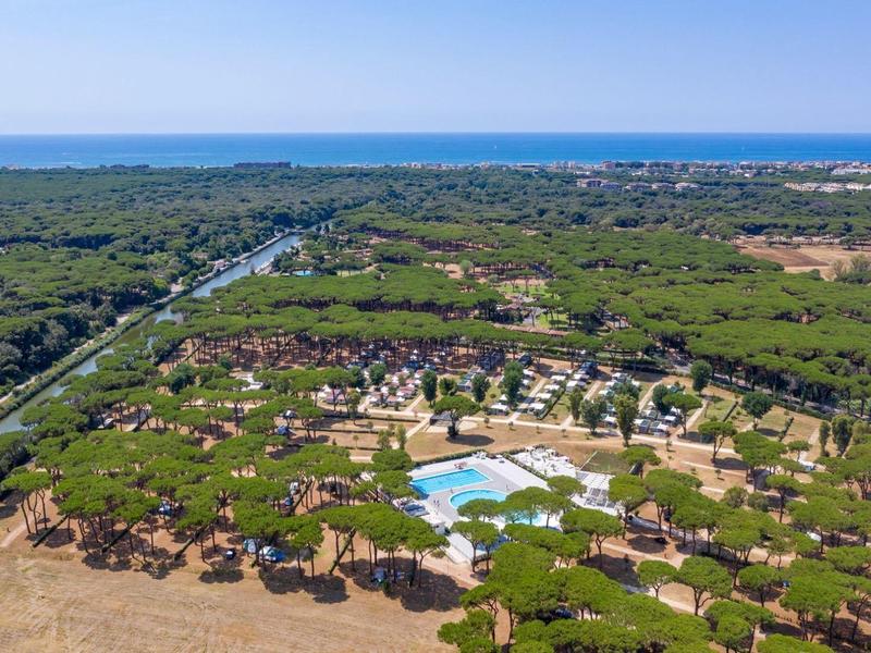 Luchtfoto van een resort met een zwembad, omgeven door bos en nabij de zee.