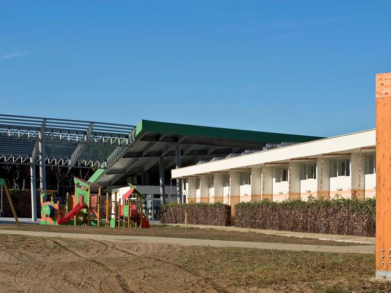 Buitengebied van een hotel met speeltuin en klimrek voor kinderen bij daglicht.