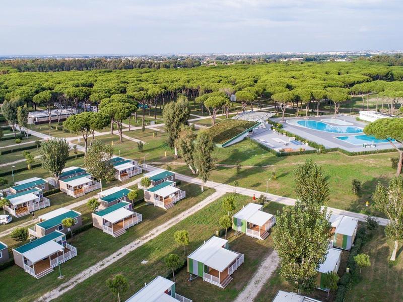 Luchtfoto van een resort met kleine moderne bungalows, zwembad en veel groen.