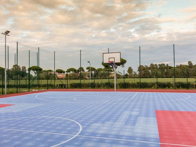 Basketbalveld met blauw-rode vloer en omringend net bij zonsondergang