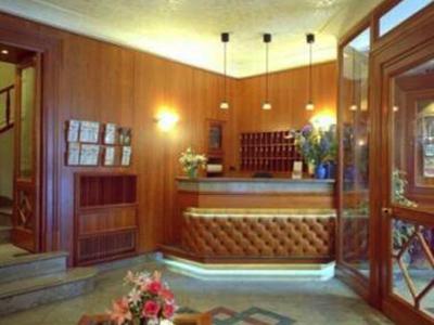 Hotelrezeption mit Holzverkleidung, Empfangstresen und Blumenarrangements in einem warm beleuchteten Raum.