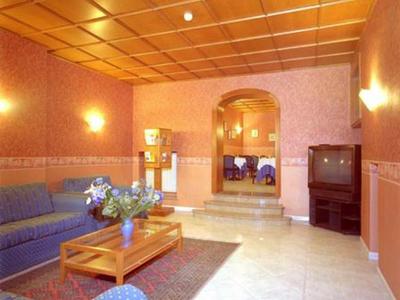 Soggiorno con divani blu, tavolo in legno, tappeto e TV in ambiente con illuminazione calda