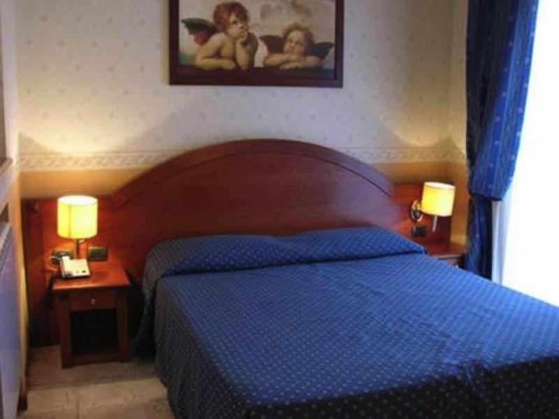 Cozy hotel room with double bed, nightstands, and warm lighting.