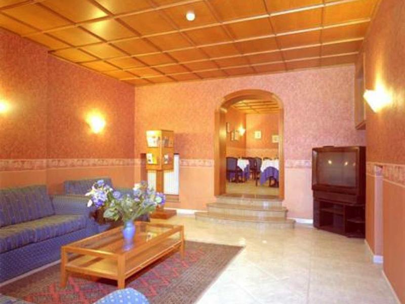 Cozy hotel lounge with blue sofas, wooden table, and retro television.