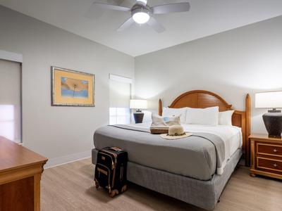 Modernes Schlafzimmer mit großem Bett, Nachttischlampe, Koffer und Deckenventilator an der Decke.